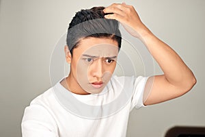 Young Asian man worrying about his hair