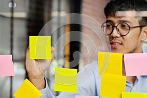 Young asian man writing on sticky note at office, business brainstorming creative ideas, office lifestyle, success in business