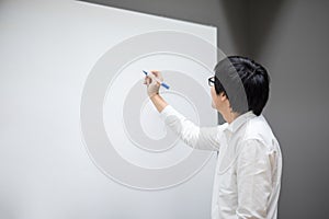 Young Asian man writing on white board in meeting room