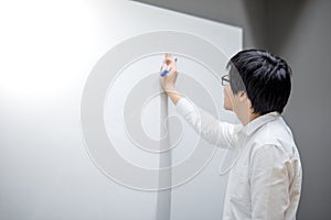 Young Asian man writing on white board in meeting room