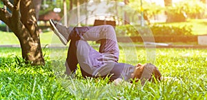 Young asian men lies on green moss relaxing with eyes closed and hands behind his head, feeling comfortable on the grass field