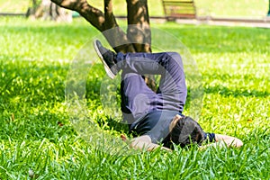 Young asian men lies on green moss relaxing with eyes closed and hands behind his head, feeling comfortable on the grass field