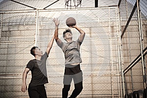 Young asian men playing basketball outdoors