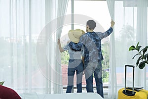Young Asian man and women are preparing for the journey happily. Young couple relaxing In room looking out of window