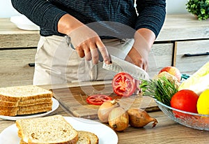 Young Asian mom preparing sandwich for lunch box for schoolboy.