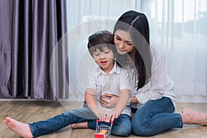Young Asian mom and son playing toy in house. Mother and son concept. Happy family and Home sweet home theme. Preschool and Back