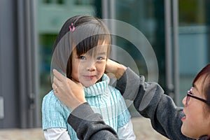 Young Asian mother adjusting her daughters hair