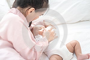 Young asian mother hold in arms and feed baby newborn from milk bottle. Portrait cute newborn baby being fed by mother using