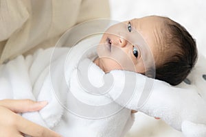 Young Asian mother hugging a cute newborn baby looking in white bedroom. Duty of the wife to raise children. Mother and child