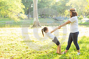 Young asian mother and little daughter playing the park with fun and happiness, family enjoy and relax and leisure together