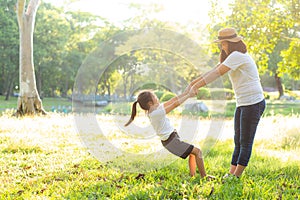 Young asian mother and little daughter playing the park with fun and happiness, family enjoy and relax and leisure together