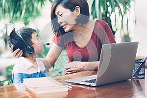 Young asian mother and son using laptop computer for study and learning together at home.
