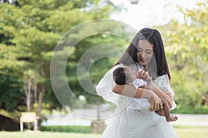 Young Asian mothers or single mom are smiling and carrying newborn babies. Family doing activities and relaxing in the park.