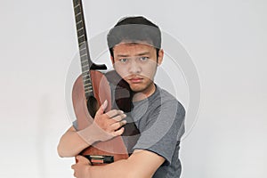 Young Asian musician who is sad by hugging his guitar