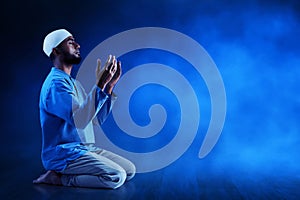 Young asian muslim man with beard praying on dark blue backgrounds