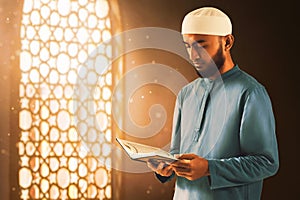 Young asian muslim man with beard read holy book quran in the mosque