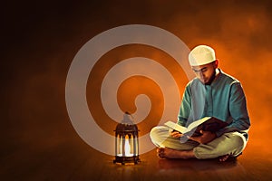 Young asian muslim man with beard read holy book quran in the mosque at dark night