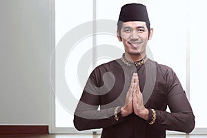 Young asian muslim man with black cap praying