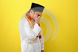 Young Asian Muslim man feel sad with covering his face with hands. Copy space concept photo