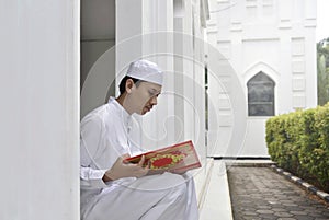 Young asian muslim man reading the holy book Quran