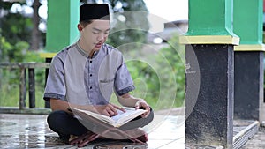 Young Asian Muslim man reading holy Qur`an on Ramadan Kareem