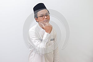 young Asian muslim man smiling and looking at camera, making thumbs up hand gesture. Isolated image on white