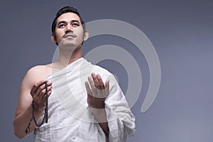 Young asian muslim man wearing ihram clothes with prayer beads