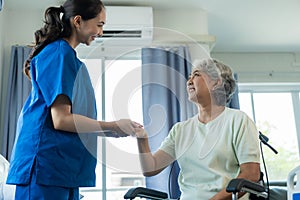 A young Asian nurse at a nursing home takes care of a senior woman. The attending physician provides physical therapy services