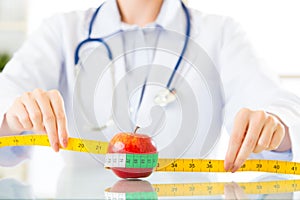 Young asian nutritionist doctor measuring an apple