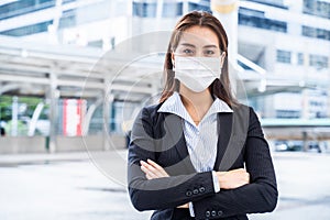 Young Asian office business woman standing outdoor in city with new normal lifestyle. People wearing protective face mask to preve
