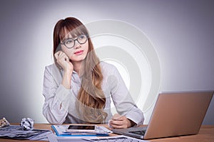 Young Asian office woman at a modern office desk, working with laptop, no concentration with job, feel boring