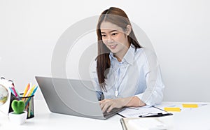 Young Asian office worker presses her finger on a laptop keyboard to analyze financial data and summarize her work in a private of