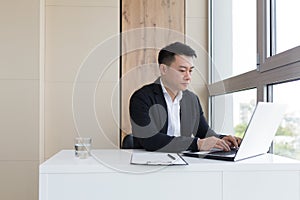 Young asian office worker suffering from headache at work in the office drinks medicine pill with water.