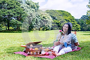 Young Asian in park.they are having a picnic and relax time.A man read abook.