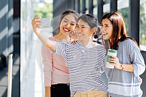 Young Asian people taking selfie photos together inside the glass building