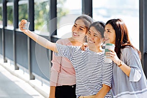 Young Asian people taking selfie photos together inside the glass building