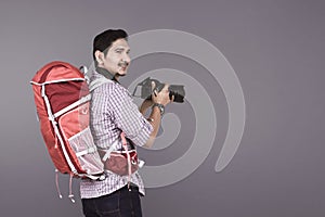 Young asian photographer with backpack holding camera