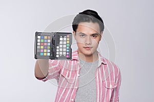 Young asian photographer holding color checker card, while working in studio