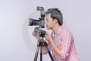 Young asian photographer holding digital camera, while working i