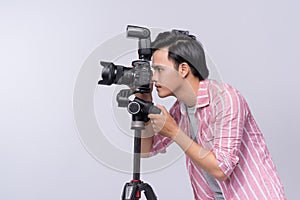 Young asian photographer holding digital camera, while working i