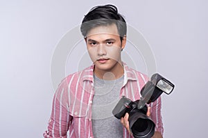 Young asian photographer holding digital camera, while working i