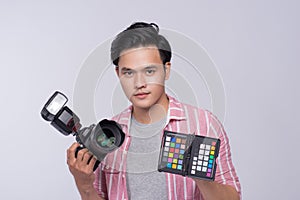 Young asian photographer holding digital camera, while working i