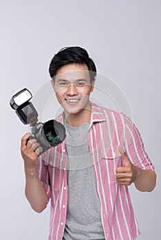 Young asian photographer holding digital camera, while working i