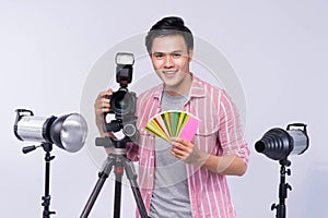 Young asian photographer holding digital camera, while working i