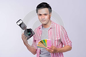 Young asian photographer holding digital camera, while working i