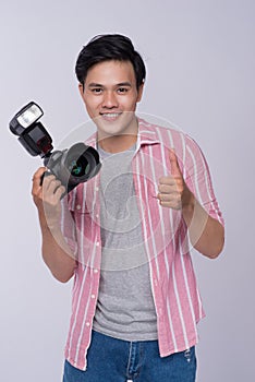 Young asian photographer holding digital camera, while working i