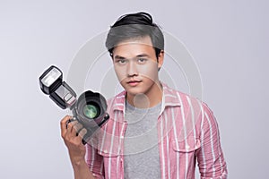 Young asian photographer holding digital camera, while working i