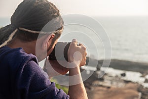 Young Asian photographer taking a picture from the top of a mountain