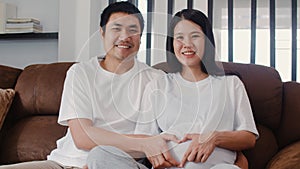 Young Asian Pregnant couple making heart sign holding belly. Mom and Dad feeling happy smiling peaceful while take care baby,