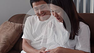 Young Asian Pregnant couple making heart sign holding belly. Mom and Dad feeling happy smiling peaceful while take care baby,